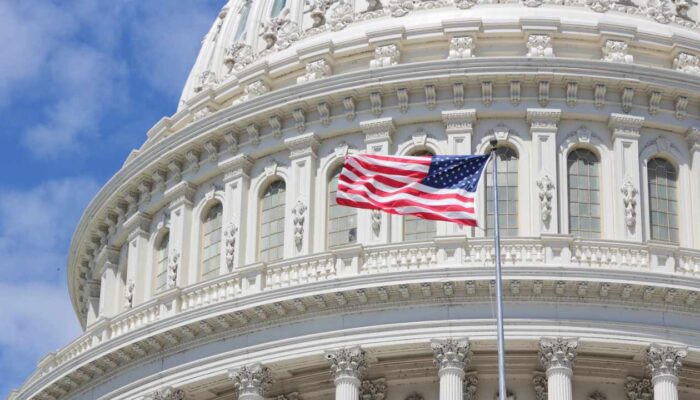 An illustration featuring the U.S. Capitol, the White House, cryptocurrency symbols, blockchain graphics, and policy documents representing the CLARITY Act and proposed crypto ethics rules.