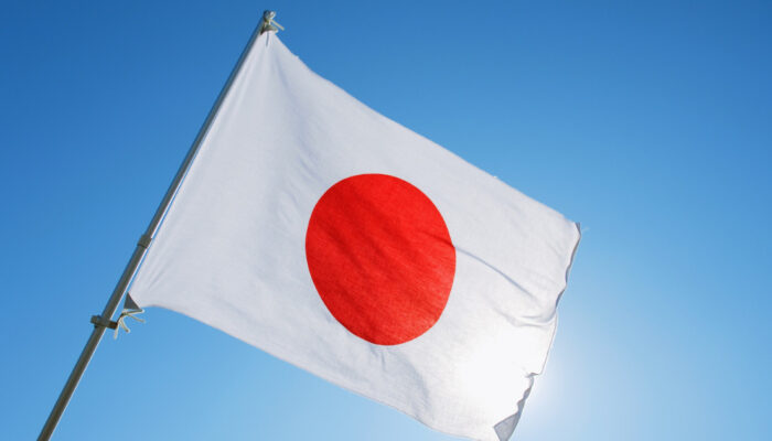 Japan's flag alongside cryptocurrency symbols, financial market charts, blockchain technology graphics, and government regulatory documents representing crypto tax reform