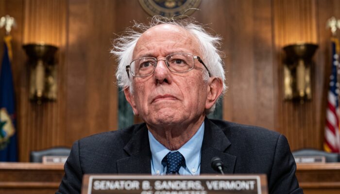 Senator Bernie Sanders speaking at a podium superimposed with digital neural network circuits and the US Capitol dome.